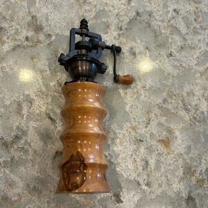 Antique style pepper grinder with wooden base.